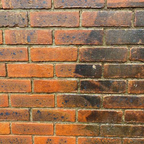 Brick wall before and after pressure washing to clean off the dirt and grime